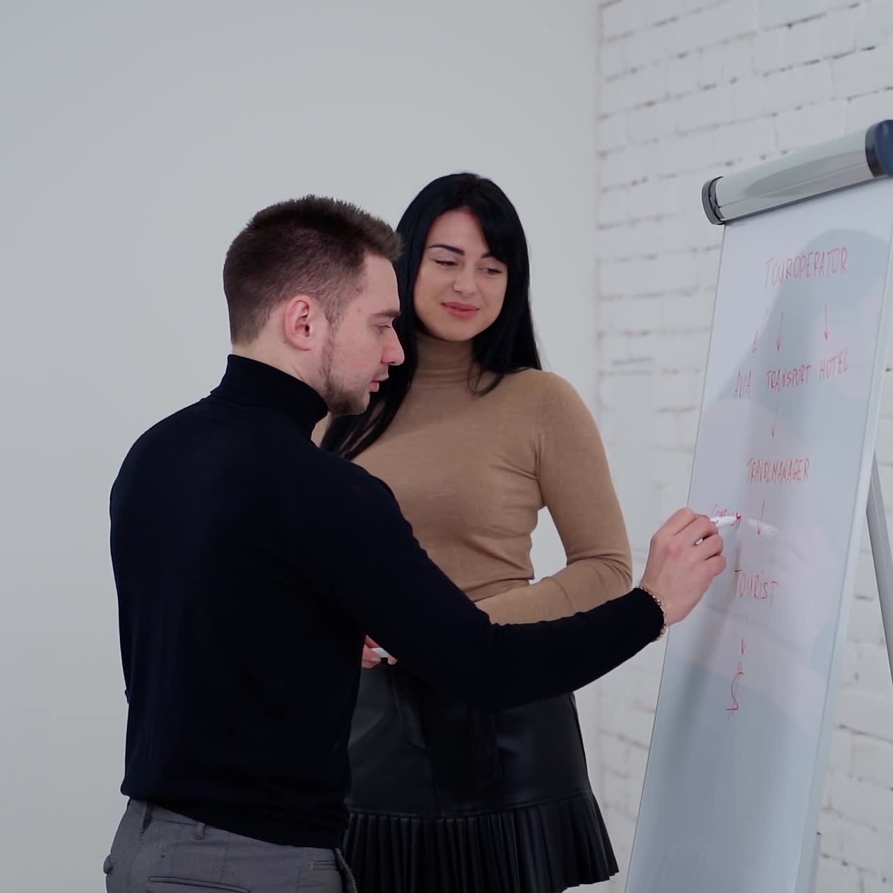 Young partners making new business plan. Handsome businessman is writing on a white board. Beautiful woman talking to a man in the office.