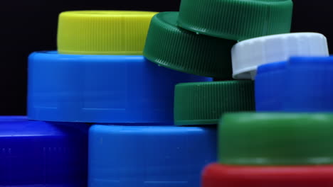 composition pyramid of used plastic caps with different colors that turn in front of a black background