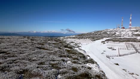 toma aerea sobre una montaña nevada hacia unas antenas y llegando a ver el horizonte en manzaneda, galicia
