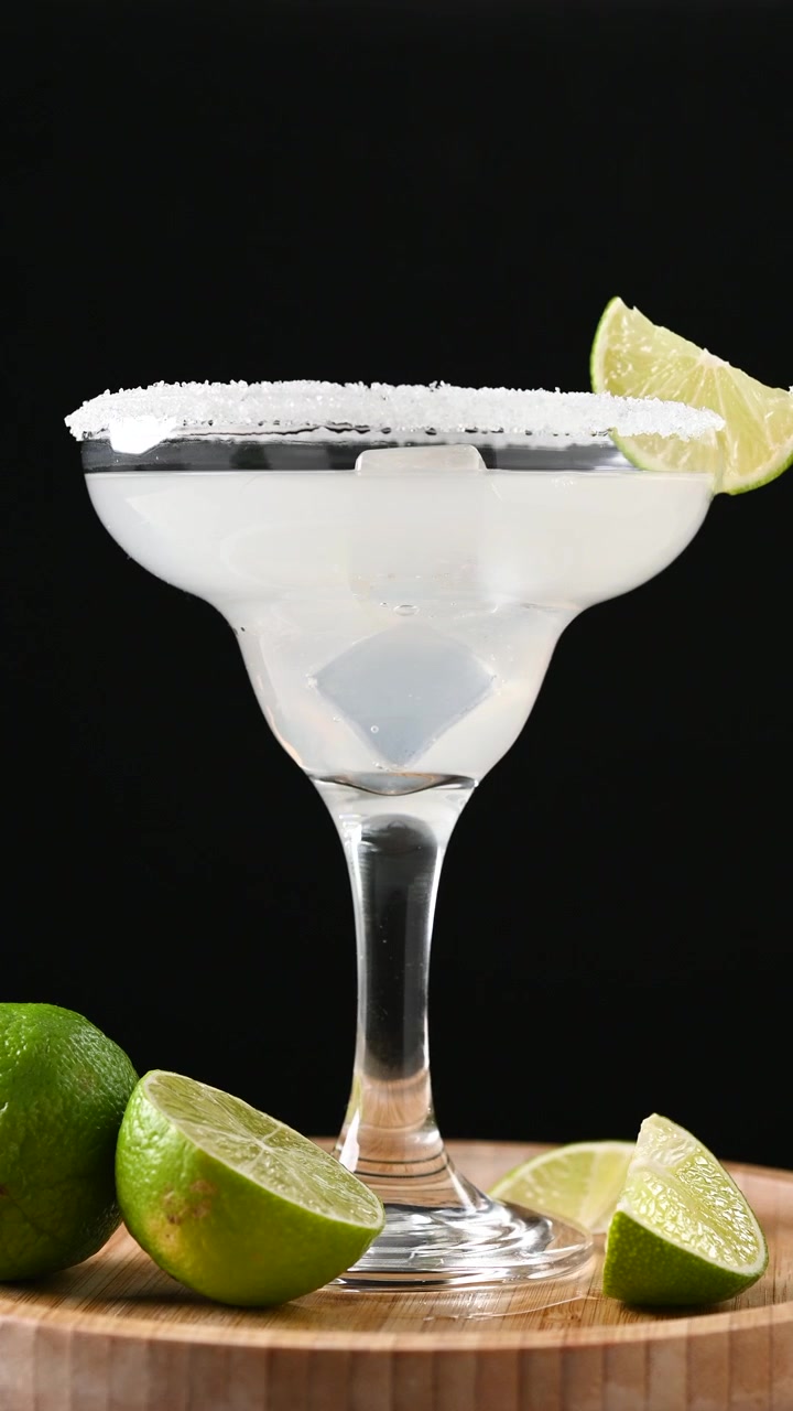 Cocktail Margarita che ruota su sfondo nero, bevanda rinfrescante agli agrumi in primo piano