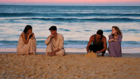 friends building sandcastles at sunset beach