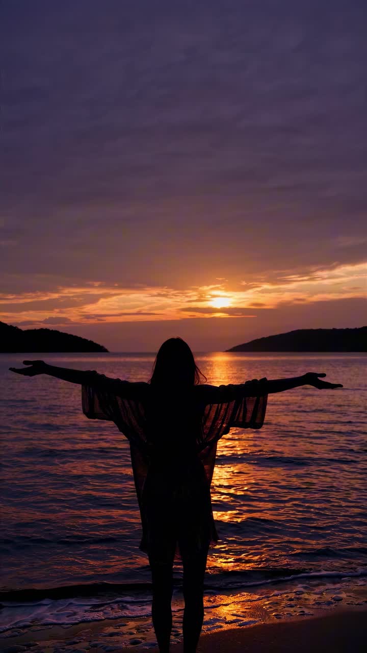 Silhouette of a person with arms outstretched at sunset on a beach