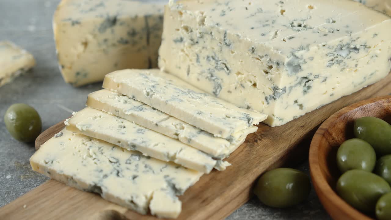 잘라낸 브리 치즈는 자르는 보드 위에 천천히 회전합니다.