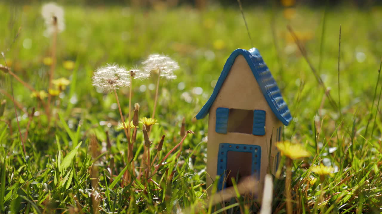 Toy house on green lawn as symbol of eco-home