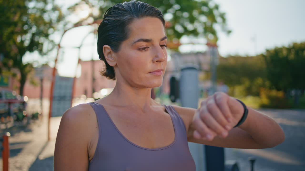 Fitness woman watching smartwatch at sunny street closeup. Lady checking results