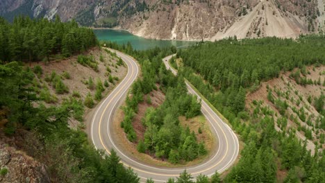 long winding u-shaped road slow aerial fly over with mountain and river view