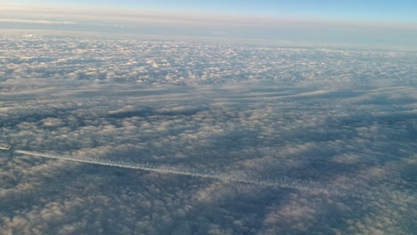 Incredible-view-from-the-cockpit-of-an-airplane-flying-high-above-the-clouds-leaving-a-long-white-condensation-vapour-air-trail-in-the-blue-sky