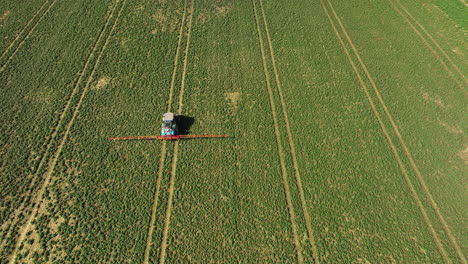 Aerial-birds-eye-of-tractor-with-trailer-spreading-liquid-manure-slurry-on-agricultural-field-at-sunlight