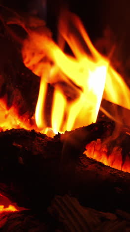 romantic fireplace. smoldering logs in hot flame burning in fireplace at home. motion of fire in wood indoors. close-up. vertical video