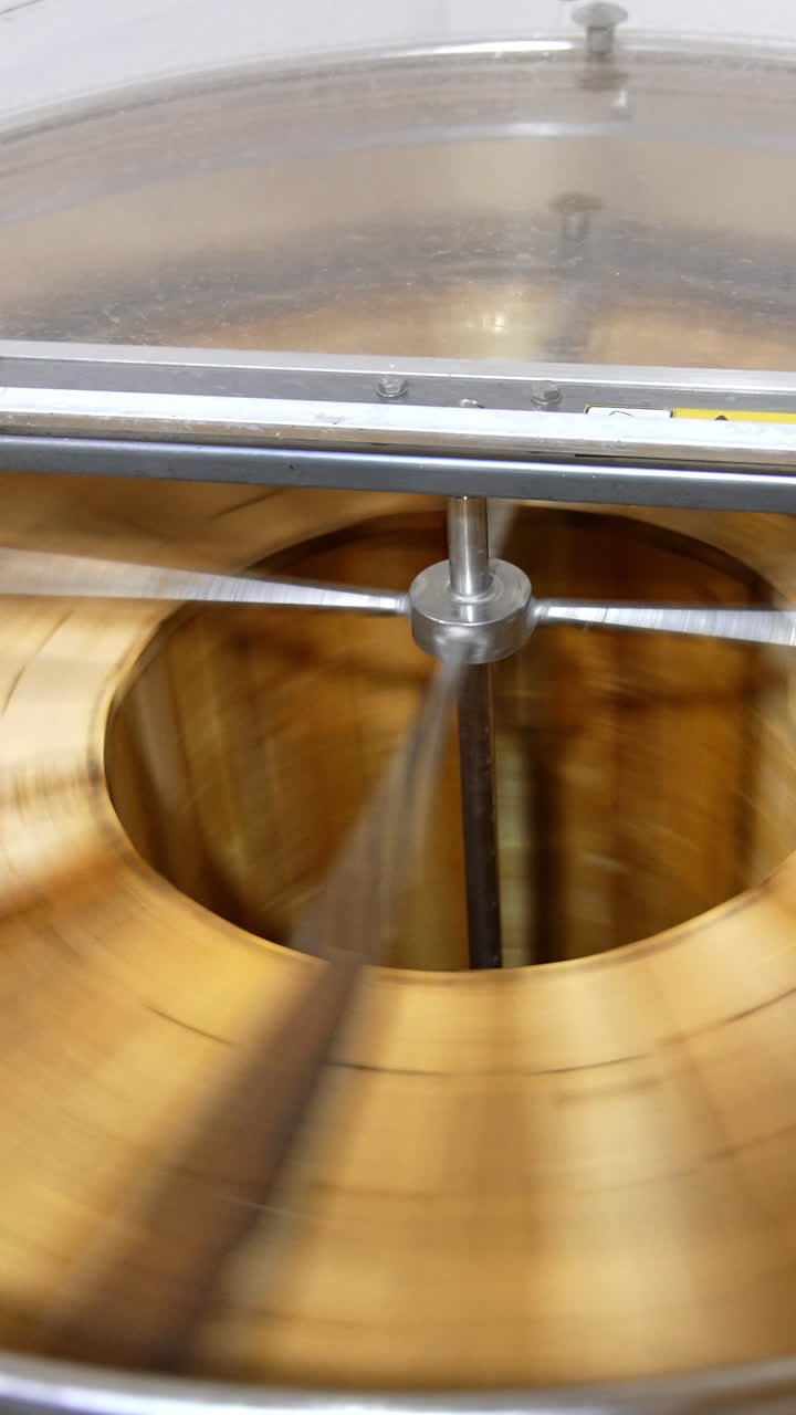 Automatic honey extracting machine rotating many frames at once. Barrel-like apparatus removing honey from honeycombs. Top view. Vertical video
