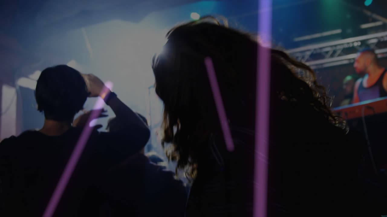 Mann med langt hår headbanger til musikk i konsert, lilla lysstriper feier over publikum
