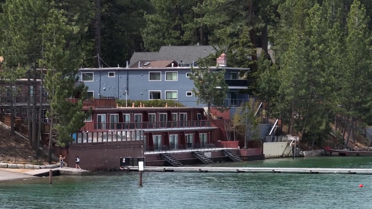Edifício residencial à beira do lago em South Lake Tahoe, Califórnia, América, Estados Unidos. Varandas, fachada de madeira, píer, cais e água calma e cristalina perto de um cenário de floresta e montanha. Tomada aérea de drone.