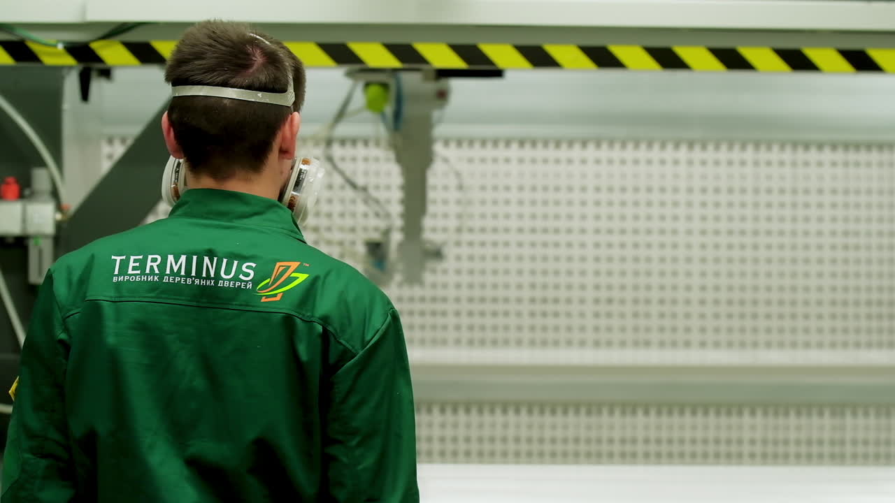 Workshop on production of doors. Worker of wood processing manufacture operating on woodworking machine