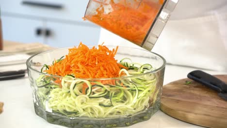 older man adding shredded carrots to spiralized salad to make zucchini noodles zoodles adding to bowl healthy vegan vegetarian lifestyle diet detox