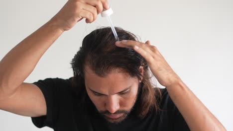 Mann,-Der-Minoxidil-Mit-Einer-Pipette-Ins-Haar-Einträgt,-Glatzenbildung