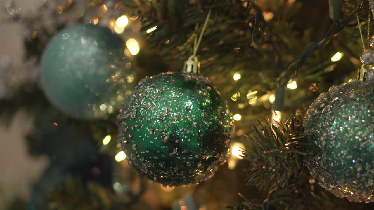 Close-Up of Sparkling Green Christmas Ornaments on a Decorated Tree with Warm Lights. 4k.