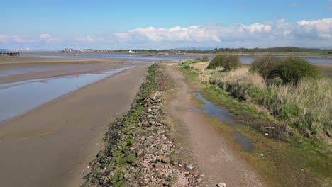 Fliegen-Entlang-Der-Küste-Zu-Einem-Einsamen-Laternenpfahl-Mit-Einer-Einsamen-Gestalt-An-Der-Mündung-Des-Flusses-Wyre,-Fleetwood,-Lancashire,-Großbritannien