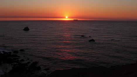 beautiful golden sunset along the northern california coast with a ship appraching the sun meeting the horizon on a calm summer night