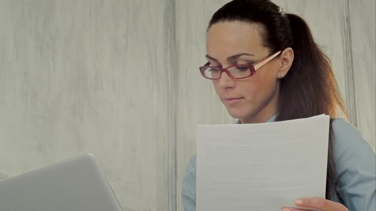 Serious attractive young woman writing notes with her laptop computer
