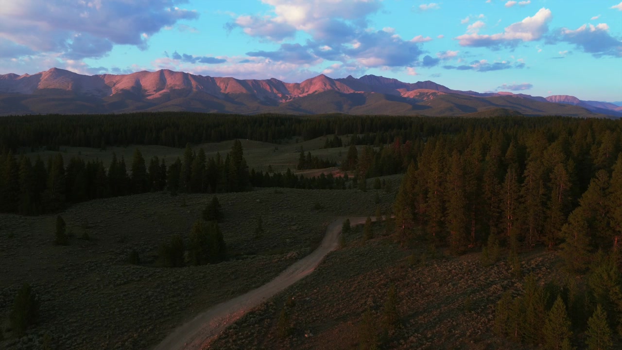 Veduta aerea con drone del paesaggio del campeggio Lakeview Campground ad Almont, Colorado, nella Collegiate Peaks Wilderness, con strada sterrata per 4x4, contea di Gunnison, tramonto estivo, catena montuosa Sawatch e bacino idrico di Taylor Park, con panoramica in avanti e verso l'alto