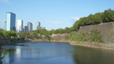 castle massive stone walls with city skyline in the background in osaka, japan. wide shot