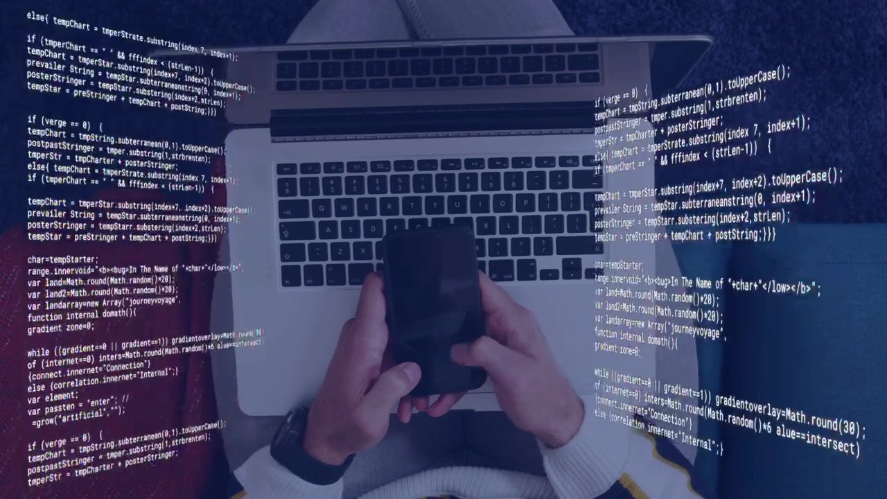 Mid-adult man checking phone, tapping trackpad then typing on laptop for coding with code overlay
