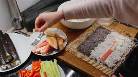 persona che aggiunge granchio sul rotolo di sushi, preparando per la cena a casa