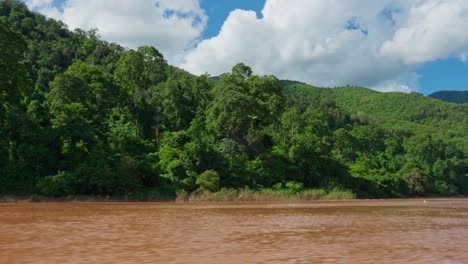 beautiful view of green hill exposing on the side of river, blue sky, white cloud