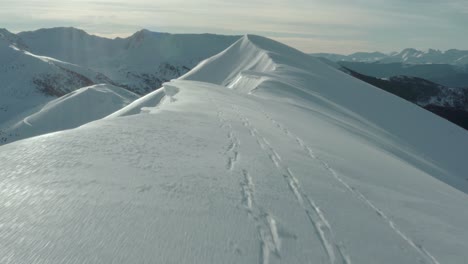 aerial: ski tracks in snow on mountain peak ridge, nature summit reveal