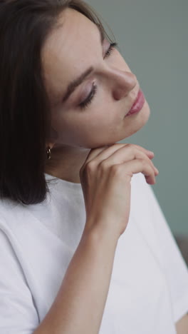 upset brunette woman with disability puts head on hand thinking about future. young female person sits in wheelchair on blurry background closeup