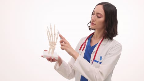 female doctor explaining hand anatomy with skeletal model