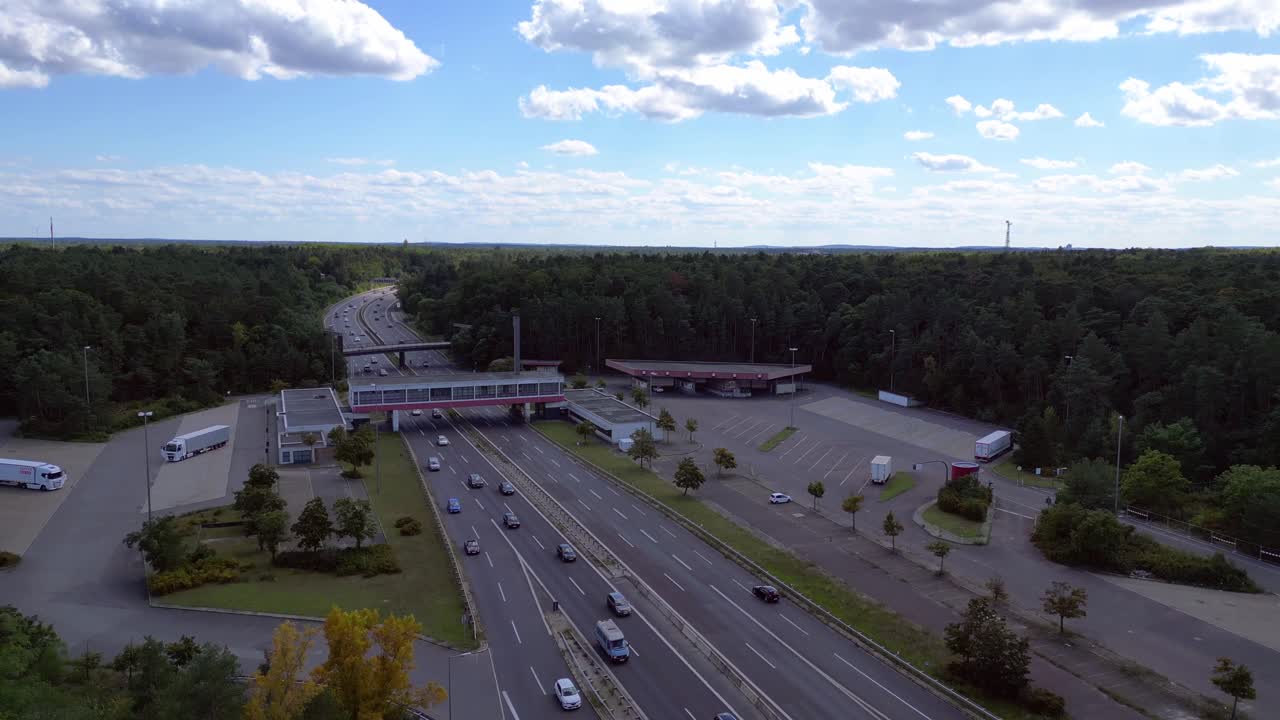 highway rest stop with cars driving on a multi lane highway. descending drone