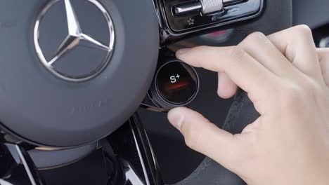 Close-Up of Hand Adjusting Driving Mode Dial Inside Mercedes Sports Car