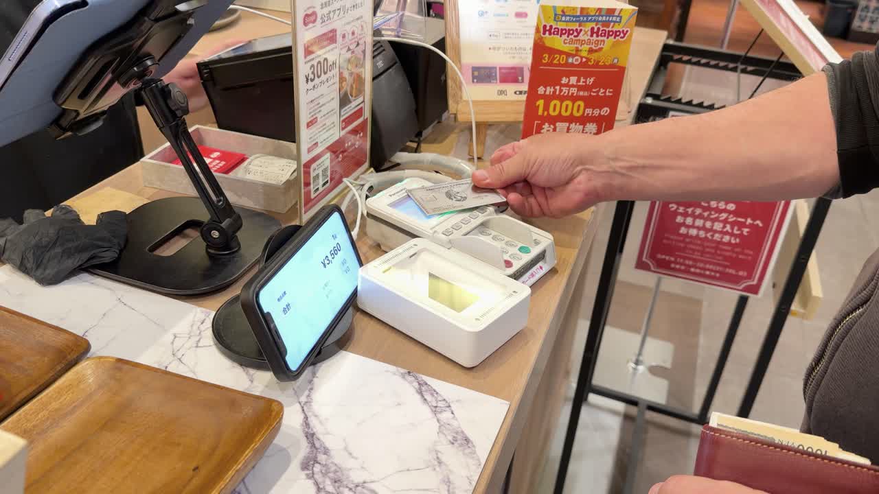 顧客が非接触決済のために端末にクレジットカードをかざす