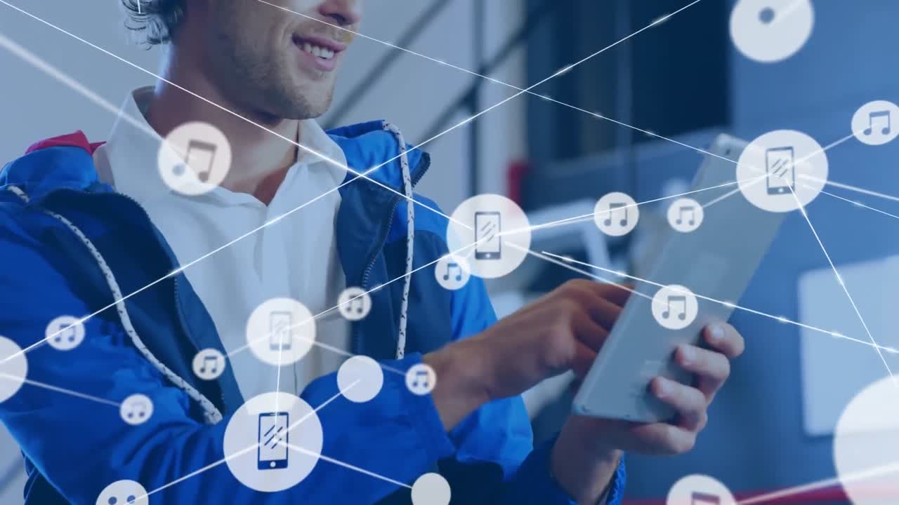 animación de una red de iconos digitales contra un hombre caucásico feliz usando una tableta digital en la oficina