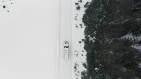 truck driving on a snowy road through a forest