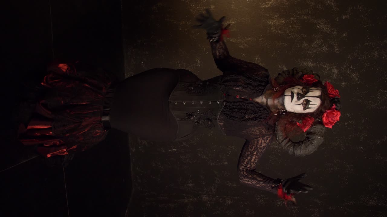 Catrina Cosplay-jente beveger hendene sakte med en mørk bakgrunn, fullskudd