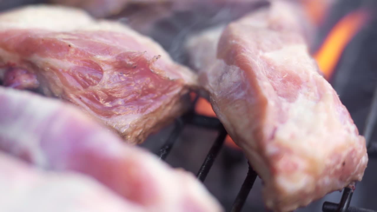 불타고 스모키한 바비큐 그릴에서 굽는 고기의 슬로우 모션 매크로