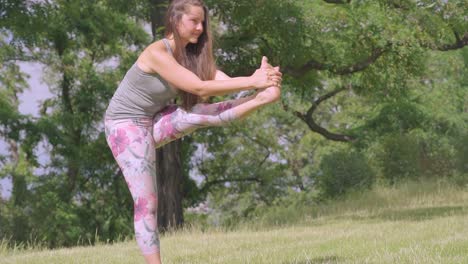 Mujer-Caucásica-Sostiene-Pose-De-Yoga-De-Piernas-En-La-Naturaleza,-Toma-De-Inclinación-En-Cámara-Lenta