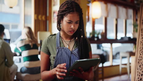 a worried employee checks a tablet in a cafe