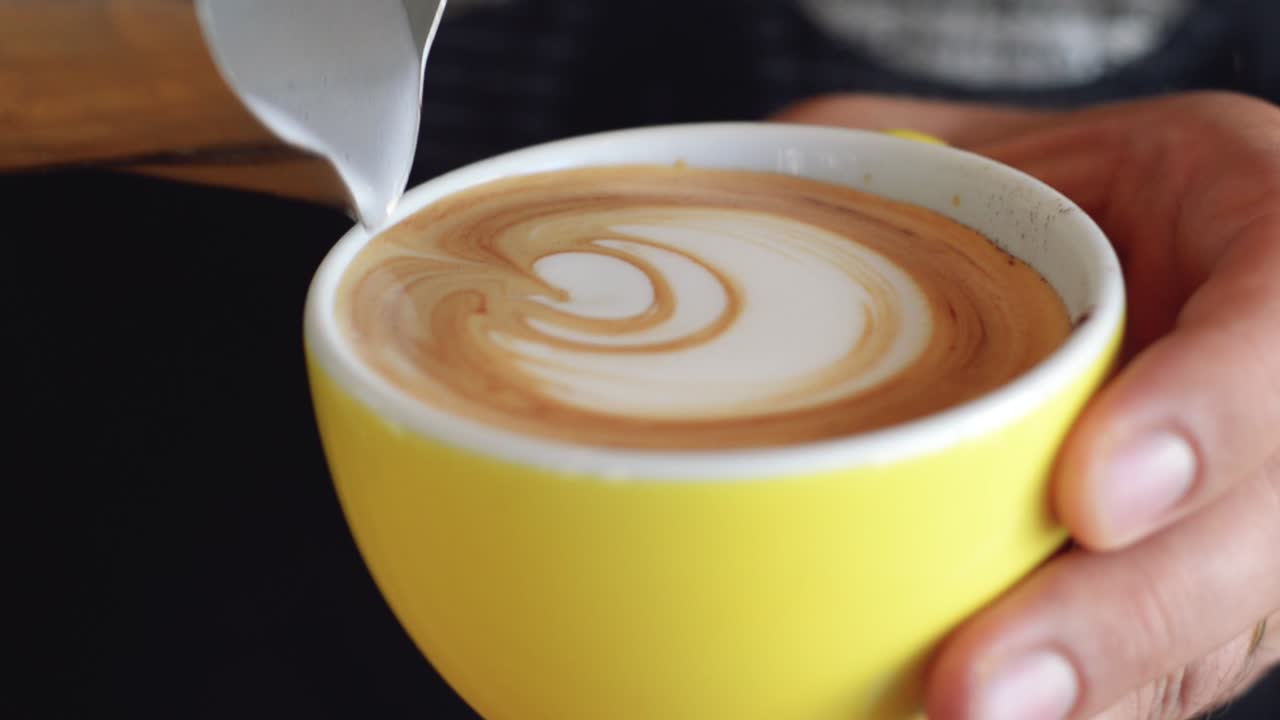 노란색 커피 컵에 로제타 패턴 라떼 아트를 붓는 숙련된 바리스타 | 미식 커피 하우스 | 시네마틱 24fps로 hd로 촬영