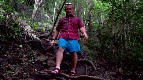 a man descends from a steep mountain along the roots of trees