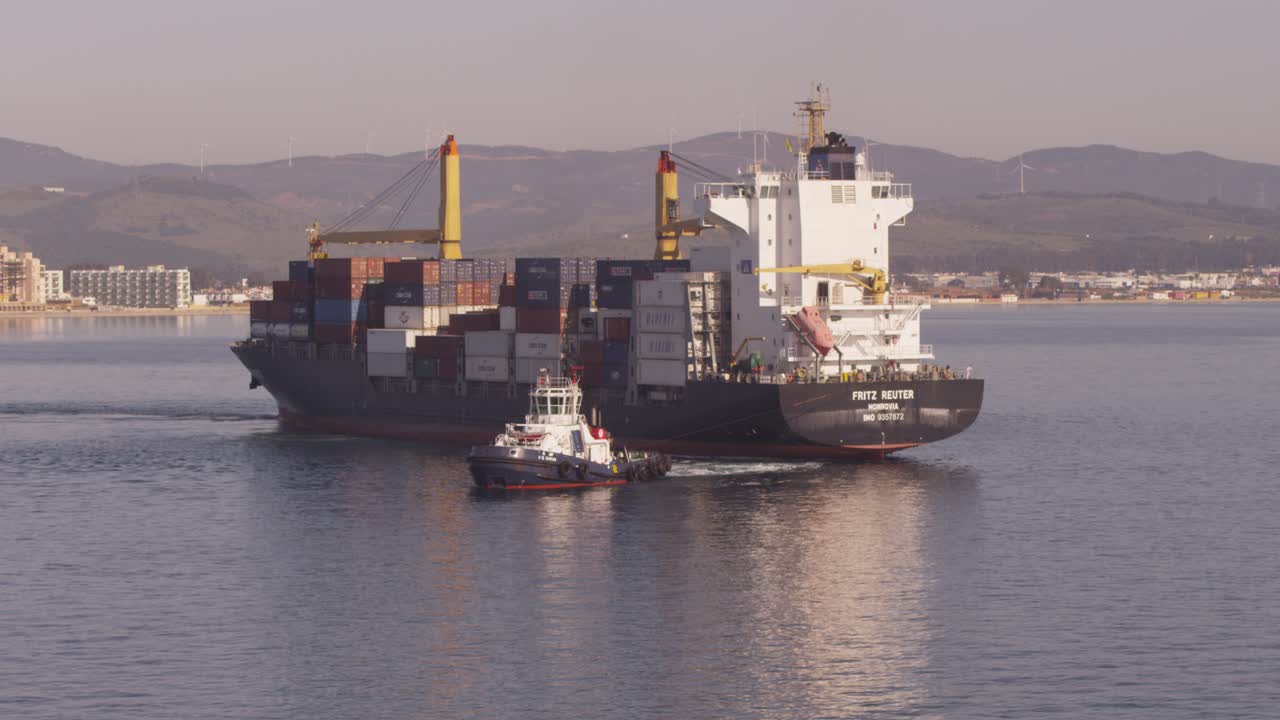Loaded container ship pulled by tug into Algeciras port