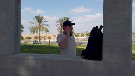young man talking on a cell phone in a park on a sunny day.