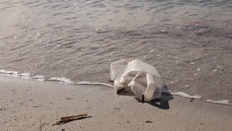 discarded plastic bottle on sandy beach with gentle waves in the background, environmental issue