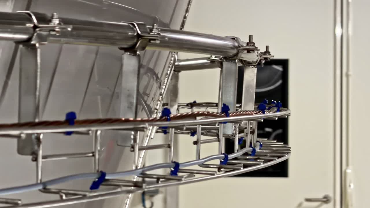 Detailed view of stainless steel machinery components with blue wiring in an industrial setting. Suitable for manufacturing or engineering content