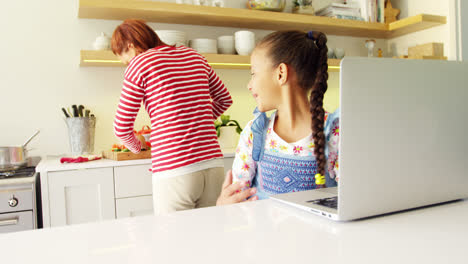 madre e hija usando portátil en el escritorio de la cocina 4k