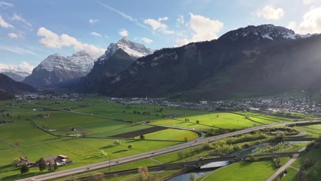 aerial of lush green valley near walensee, weesen, switzerland, with sprawling fields and majestic snow-capped mountains under clear sky