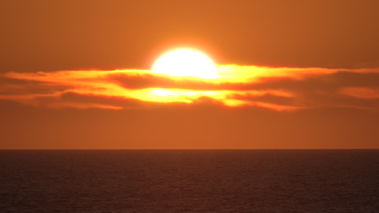 Solnedgang over havet, et fredfyldt og roligt øjeblik. Solopgang med en stor orange sol.