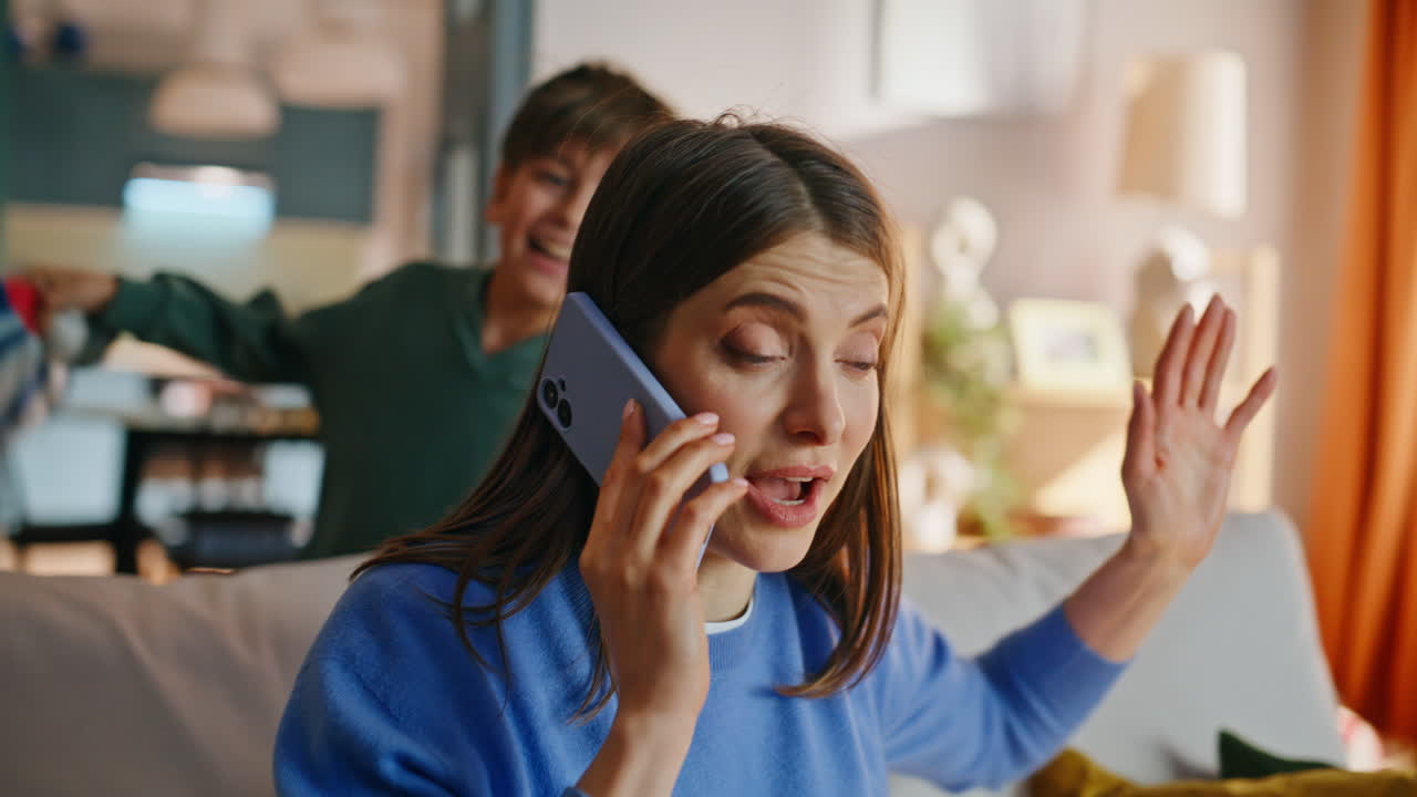 Son bothering mother calling cellphone sitting couch closeup. Stressed woman